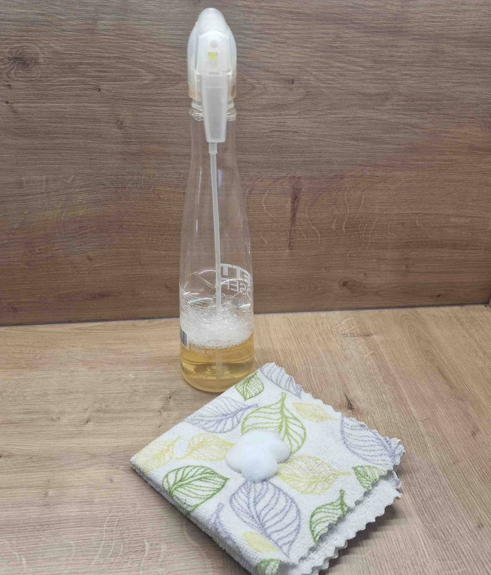Getesteter Fettlöser befindet sich mit einem Küchentuch auf einem Holztisch. 