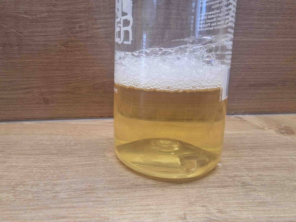 Detailansicht des schäumenden Inhalts einer Flasche getesteter Fettlöser.