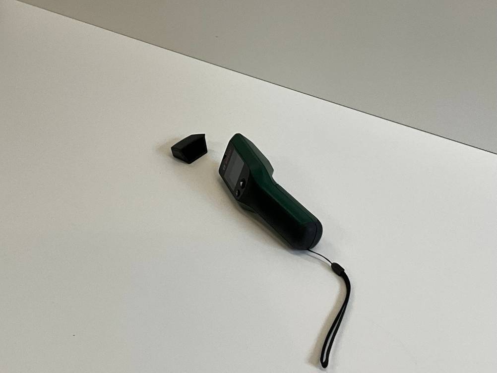 Im Test: Ein Bosch Feuchtigkeitsmessgerät von schräg hinten auf der Seite liegend auf einer hellen Fläche.