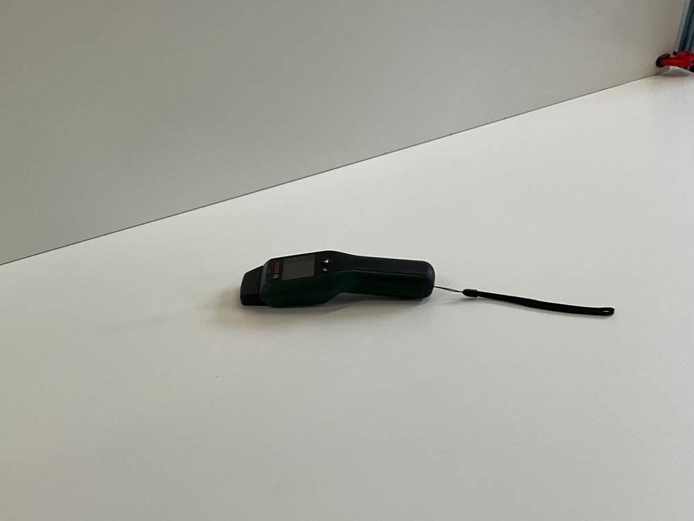 Seitenansicht eines getesteten Bosch Feuchtigkeitsmessgerät auf einer hellen Fläche.
