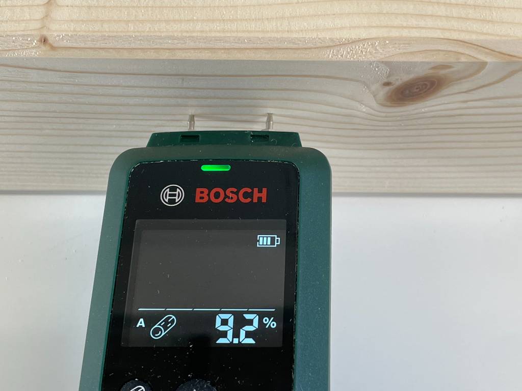 Ein Feuchtigkeitsmessgerät von Bosch misst die Feuchtigkeit einer Holzplanke.