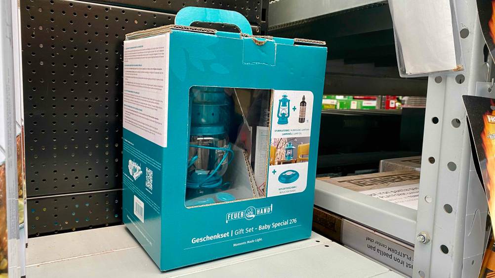 Eine getestete Sturmlaterne in ihrer Originalverpackung von schräg vorne in einem Regal.