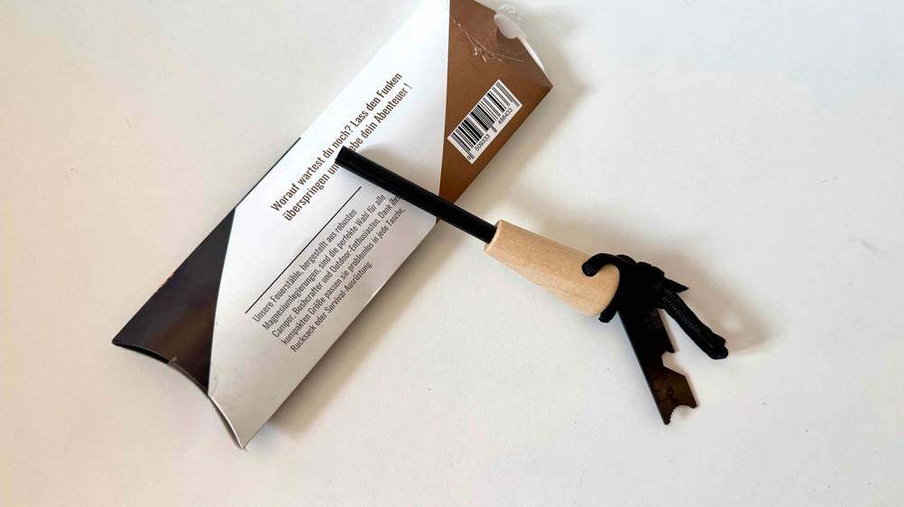 Ein getesteter Feuerstahl liegt leicht auf der Rückseite der Originalverpackung.