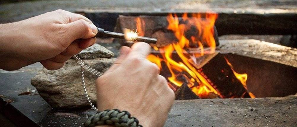 Feuerstahl-Test: Eine Person verwendet vor einem Feuer einen Feuerstahl. 