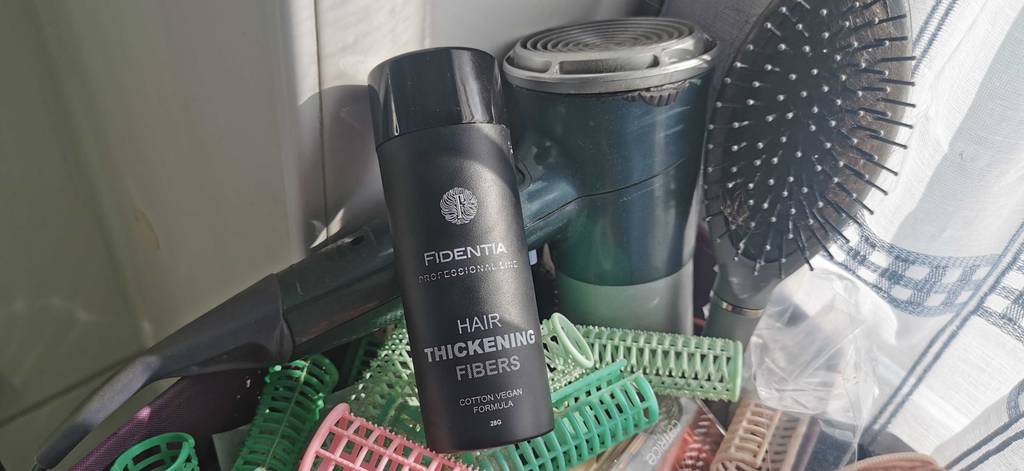 Streuhaar im Test: Eine schwarze Streudose von Fidentia befindet sich auf Haarstyling-Utensilien.