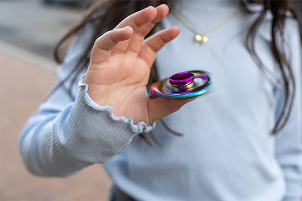 Fidget Spinner im Test: Ein Mädchen mit einem Fidget Spinner aus Metall.