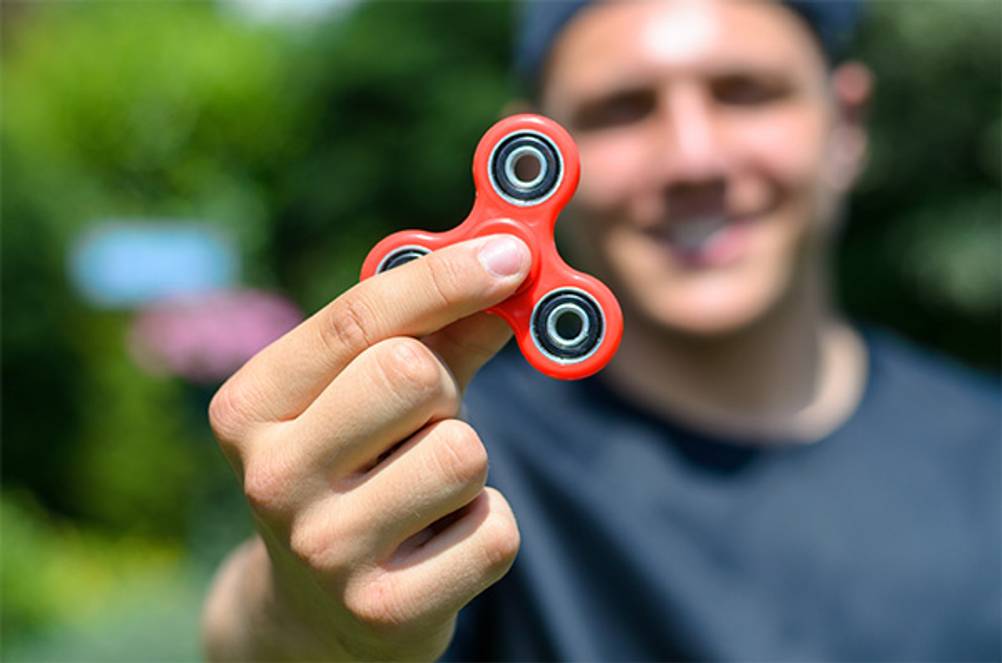 Fidget Spinner im Test: Ein Mann, der einen roten Fidget Spinner in die Kamera hält.