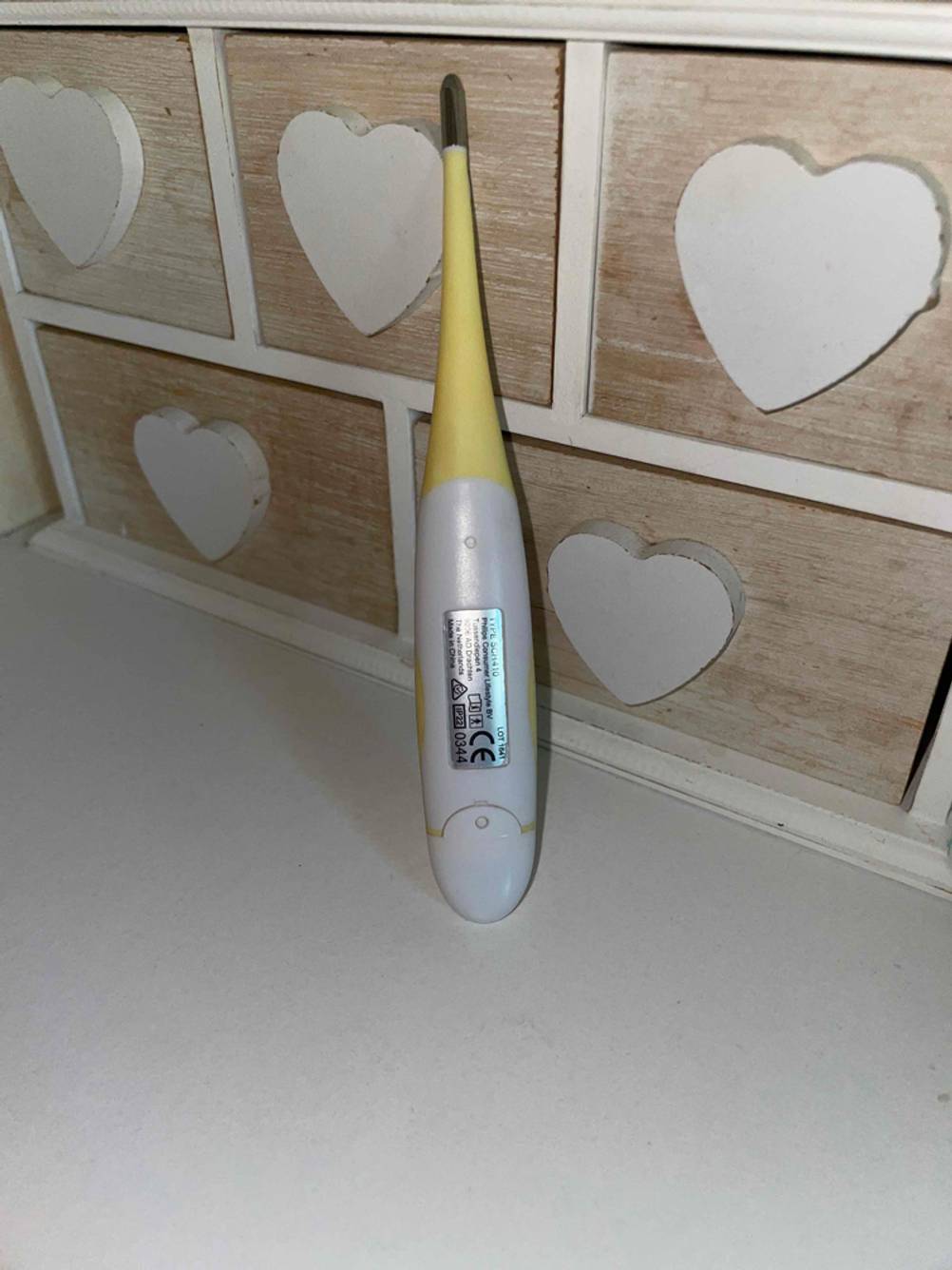 Baby-Fieberthermometer getestet: Ein Gerät von hinten an einer Holzbox lehnend.