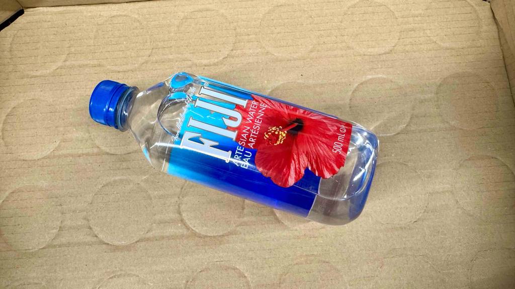 Quellwasser im Test: Eine Kunststoffflasche mit FIJI-Wasser liegt auf einem braunen Karton.