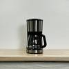 Die WMF Bueno Filterkaffeemaschine steht allein auf einer Holzfläche. Die Kanne ist leer und das Gerät nicht in Betrieb.