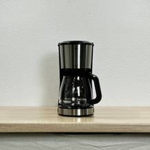 Die WMF Bueno Filterkaffeemaschine steht allein auf einer Holzfläche. Die Kanne ist leer und das Gerät nicht in Betrieb.