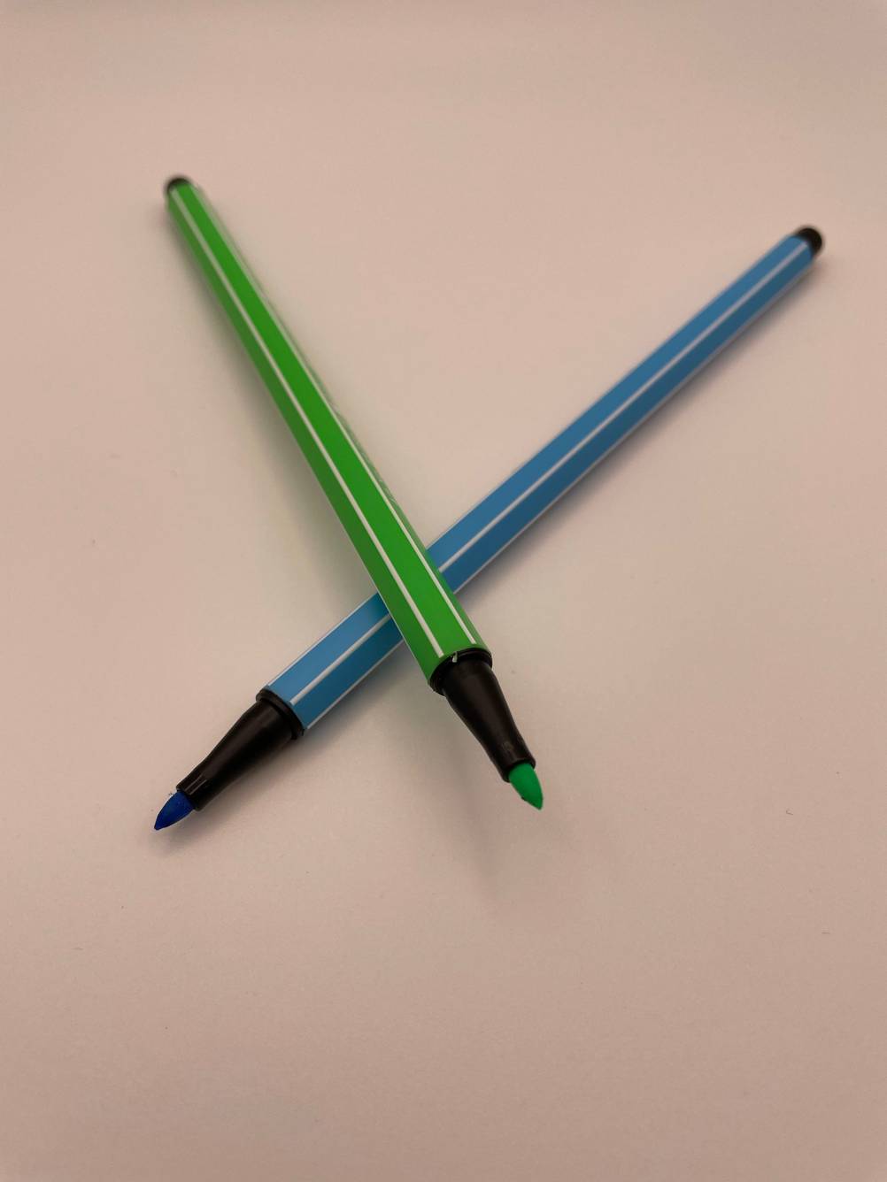 Zwei getestete Filzstifte ohne Kappe auf einer hellen Fläche.