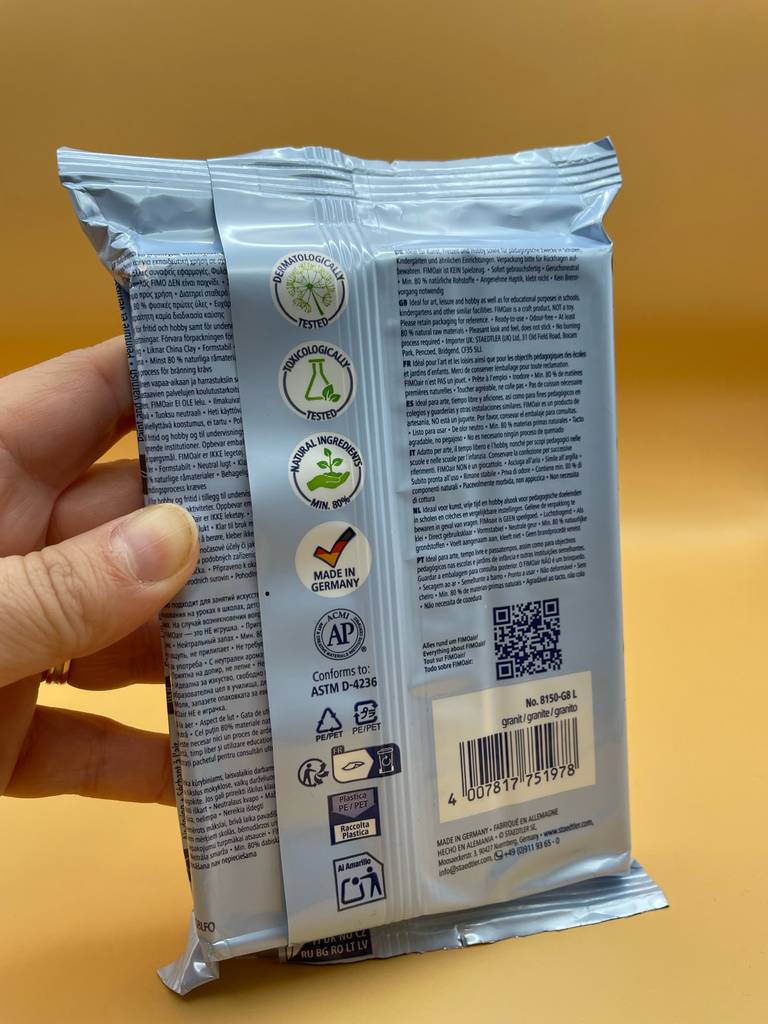 Im Test: Eine Hand hält eine Packung Fimo-Knete mit der Rückseite nach vorn.