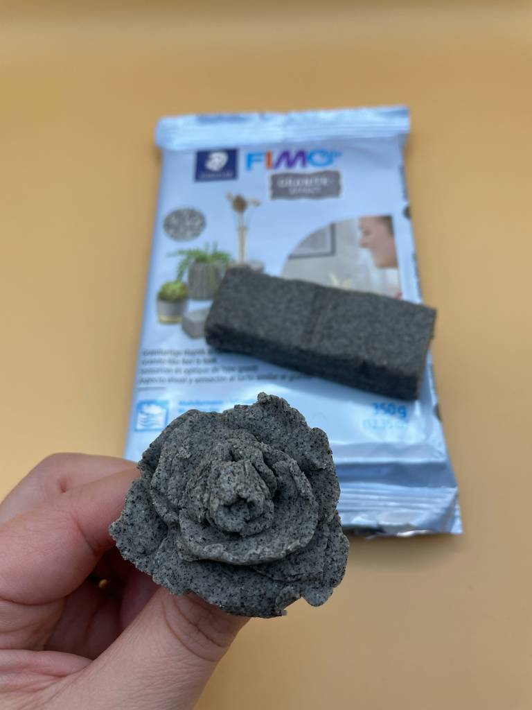 Getestet: Eine Hand hält eine aus Fimo-Knete geformte Rose, im Hintergrund die Packung.