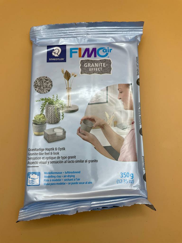 Eine Packung Fimo-Knete liegt zum testen auf einer gelben Fläche.