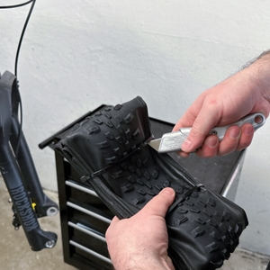 Ein Fincci-Gravel-Fahrradreifen 29 Zoll wird gerade aus der Verpackung geschnitten. Das Profil ist nur teilweise sichtbar.