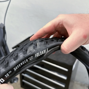 Eine Hand hält einen unaufgepumpten Fincci-Gravel-Fahrradreifen.