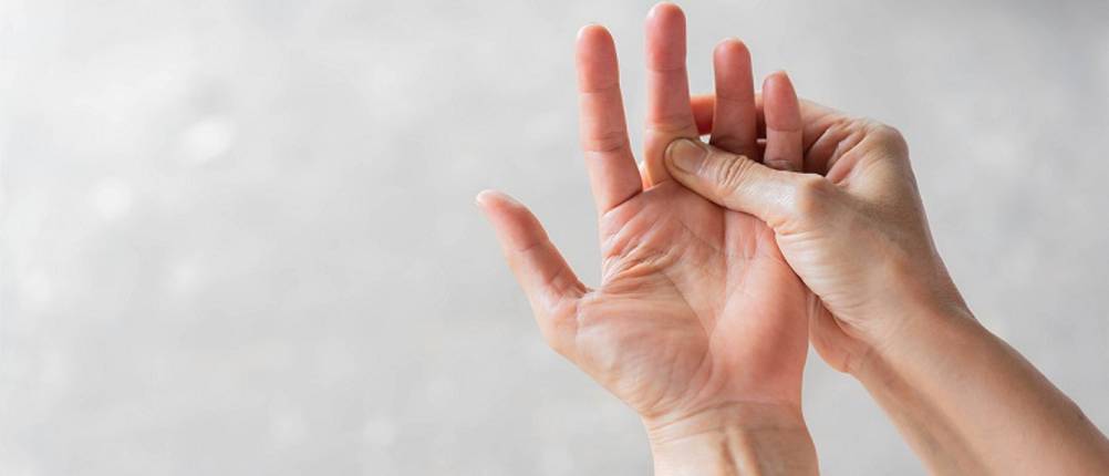 Fingerschiene getestet: Frau, die ihren schmerzenden Mittelfinger hält