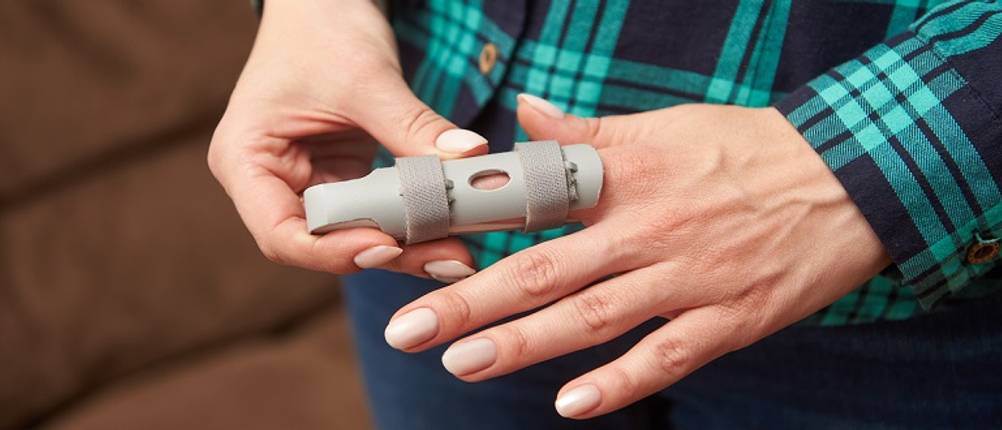 Fingerschiene im Test: Frau, die eine Fingerschiene am Zeigefinger trägt