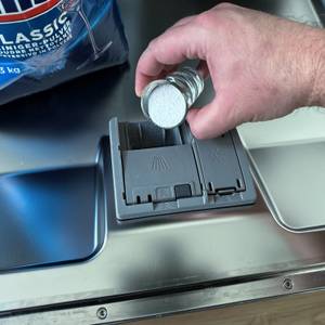 Mit Hilfe eines Shotglases wird das Finish-Spülmaschinenpulver in das Fach der Maschine gefüllt