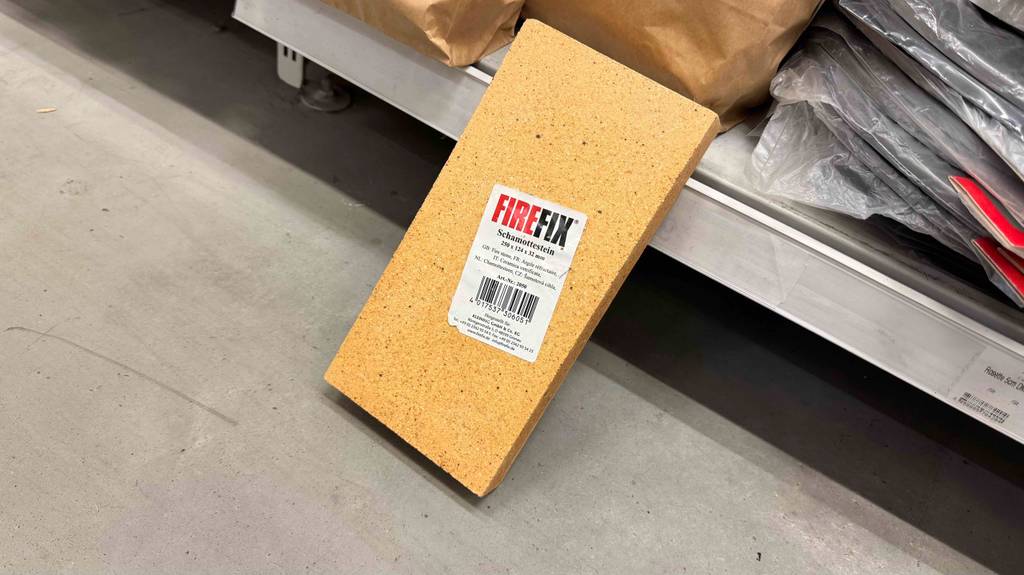 An einem Regal im Baumarkt lehnt der getestete Schamottstein in Hellgelb.
