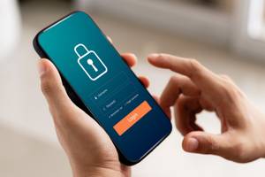 Person hält ein Smartphone mit einer Grafik eines Logins in der Hand und testet die Firewall.
