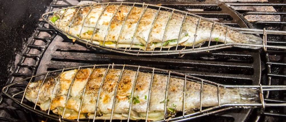 Beim Grillen getestet: Zwei Fischwender mit Fischen auf einem Grill.