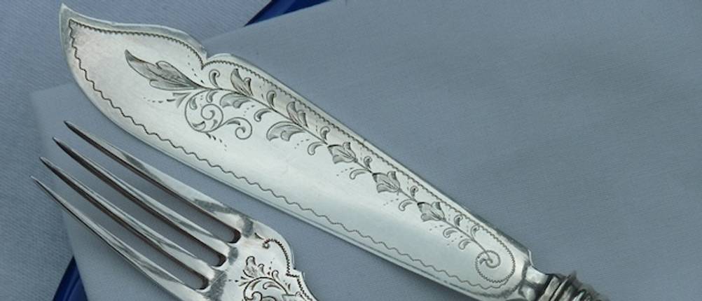 Antikes Fischbesteck im Test: Nahaufnahme von verziertem Silber-Fischbesteck.