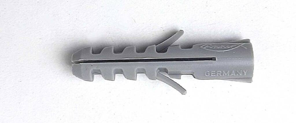 Ein grauer, getesteter Dübel von Fischer (Germany) liegt auf einer weißen Oberfläche.