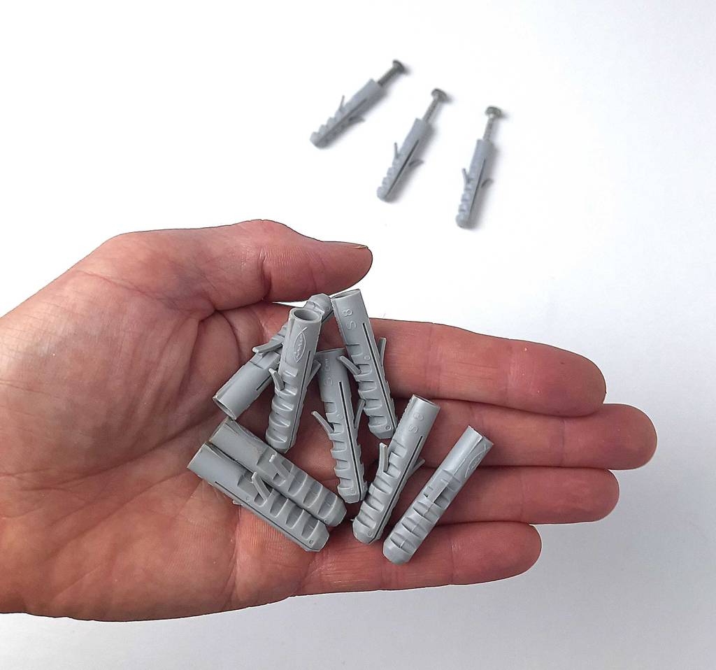 Auf einer Handfläche liegen mehrere graue Dübel im Test.