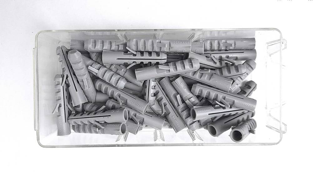 Die getesteten Dübel befinden sich in einer offenen, transparenten, von oben betrachteten Kunststoffbox.