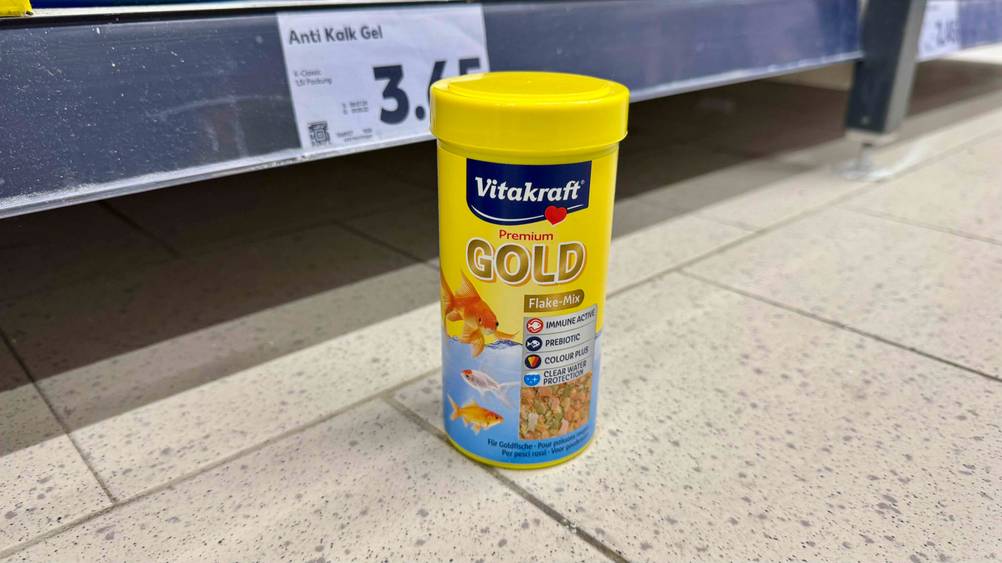 Eine Dose des getesteten Fischfutters steht vor einem Regal auf dem Boden.
