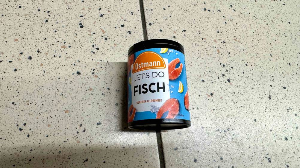 Auf dem Fließenboden liegt eine Dose Fischgewürz im Test.