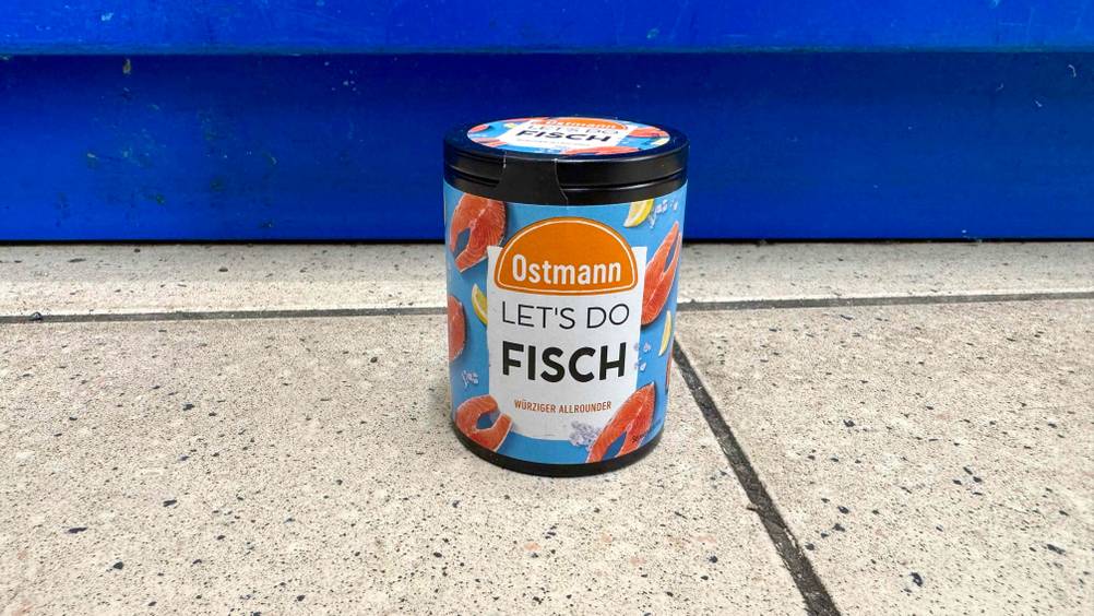 Vor einem blauen Regal steht eine Dose des getesteten Fischgewürzes auf dem Boden.