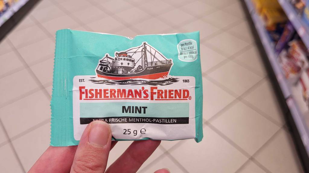 Eine Hand hält eine Packung Fishermans-Friend zum testen.