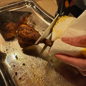 Eine Hand hält das Fleisch während dem Schneiden mit der Fiskars 1003033 FF Geflügelschere fest