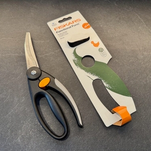 Die Fiskars 1003033 FF Geflügelschere liegt neben ihrer Verpackung auf einer Arbeitsplatte.