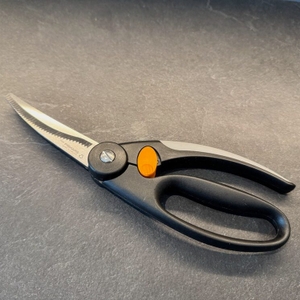 Die Fiskars 1003033 FF Geflügelschere liegt geschlossen auf einer Küchenarbeitsplatte
