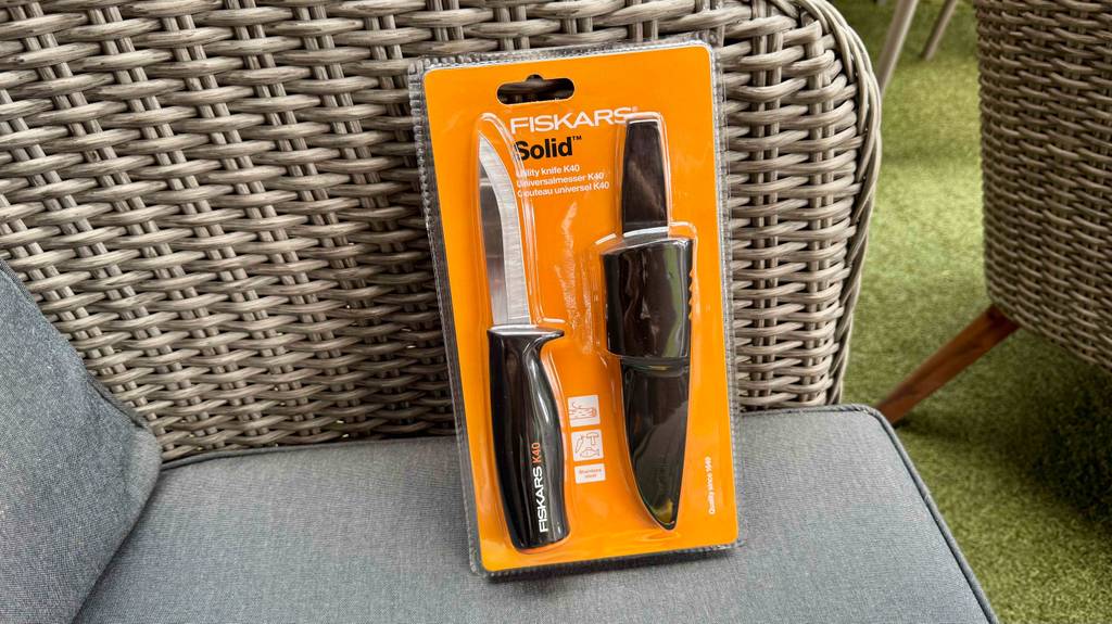 Im Test: Ein Fiskars-Messer lehnt in Originalverpackung an einen Rattanstuhl.