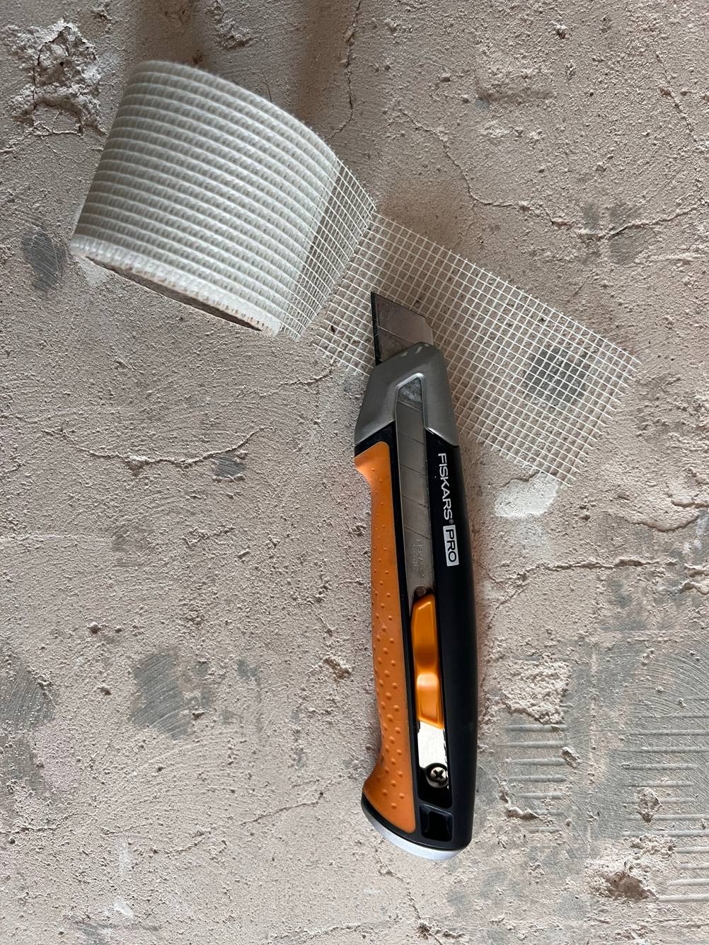 Fiskars Pro Cuttermesser neben einer Geweberolle.