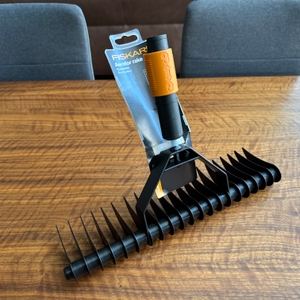 Ein Stück Karton hängt an der Messerwalze des Fiskars-Rasenlüfters.