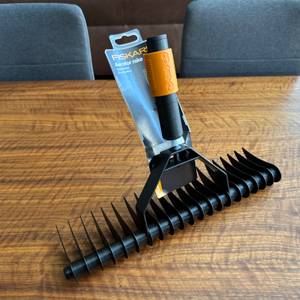 Ein Stück Karton hängt an der Messerwalze des Fiskars-Rasenlüfters.