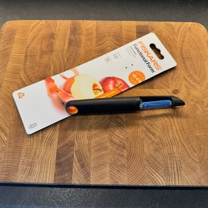 Der Fiskars Schäler und seine Verpackung liegen nebeneinander.