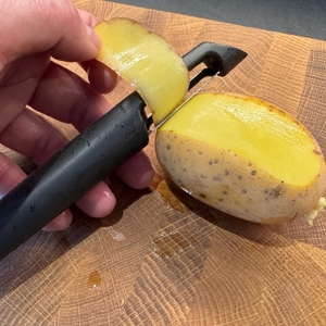 Ein Stück Kartoffelschale hängt im Fiskars Schäler.