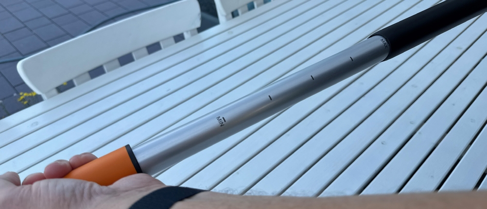 Eine Hand verstellt die Länge des Fiskars-SmartFit-Teleskop-Unkrautstechers.