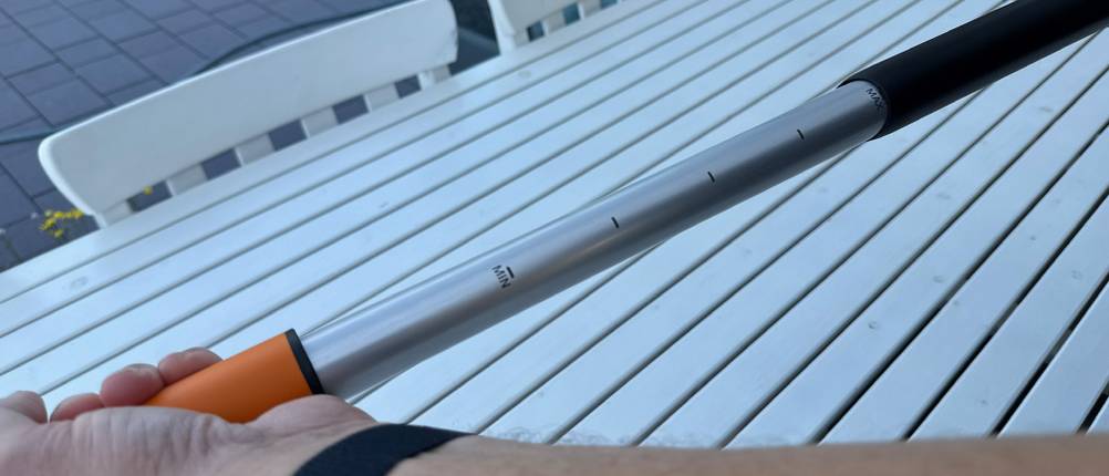 Eine Hand verstellt die Länge des Fiskars-SmartFit-Teleskop-Unkrautstechers.