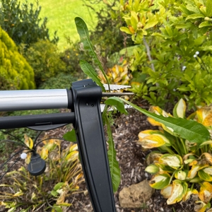 An den Spitzen des Fiskars-SmartFit-Teleskop-Unkrautstechers hängt vollständig aus dem Boden entferntes Unkraut.