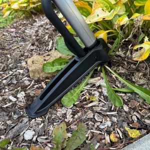 Der Fiskars-SmartFit-Teleskop-Unkrautstecher hebt Unkraut aus der Erde.