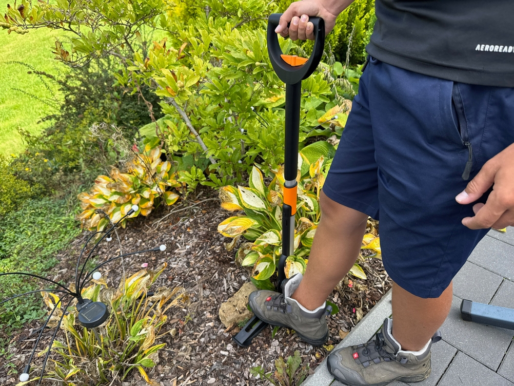 Ein Fuß steht auf dem Hebel des Fiskars-SmartFit-Teleskop-Unkrautstechers.