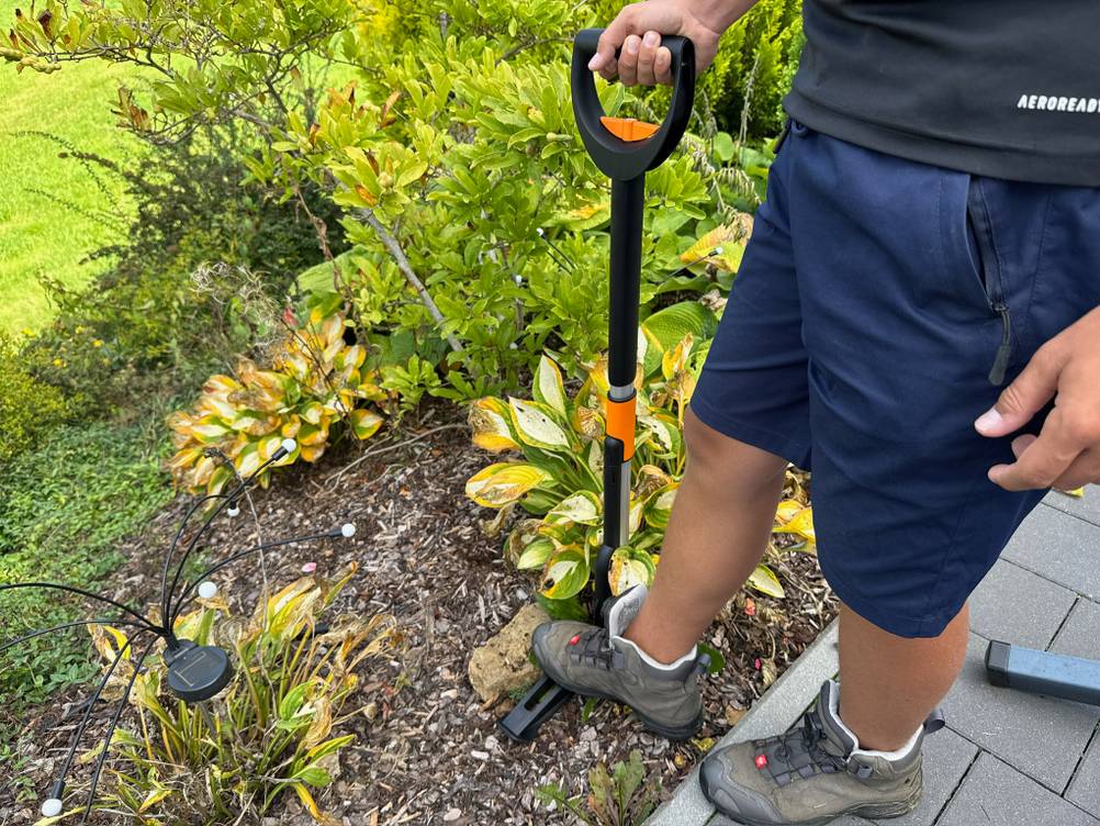 Ein Fuß steht auf dem Hebel des Fiskars-SmartFit-Teleskop-Unkrautstechers.